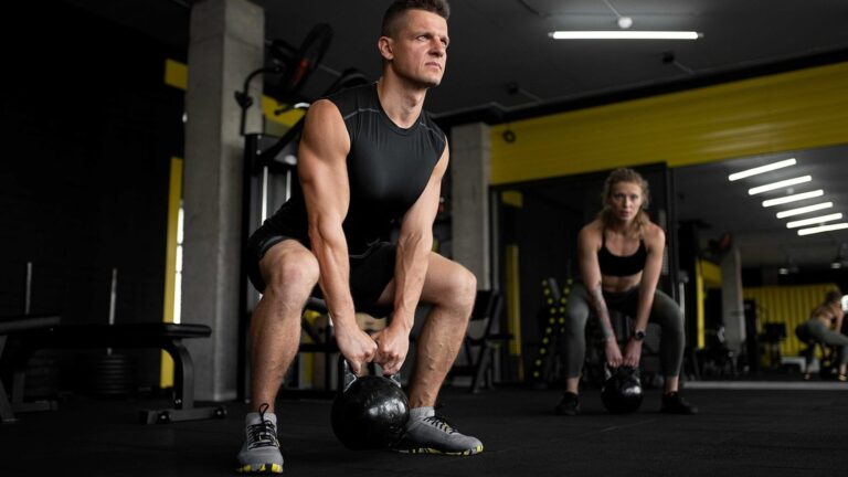 Muž zvedá kettlebell v posilovně