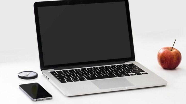 Otevřený notebook a telefon na bílém stole