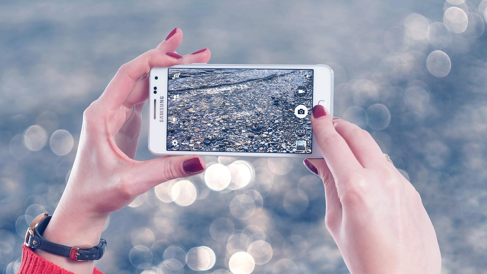 Ruce drží chytrý telefon nad vodní hladinou