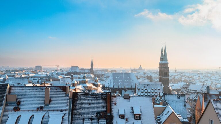 Zasněžené střechy Norimberku s věžemi kostelů