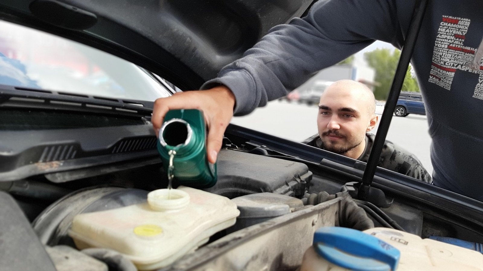 Muž dolévá chladicí kapalinu do expanzní nádobky v motorovém prostoru