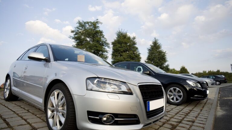 Ojeté stříbrné auto zaparkované na dlážděném parkovišti